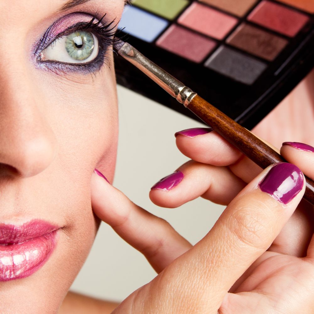Close-up of a person applying makeup with a brush and palette
