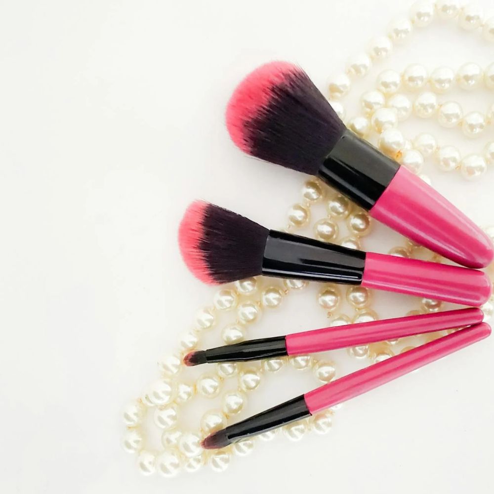 Set of makeup brushes with pink and black handles on a white background
