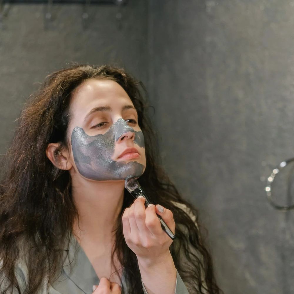 Woman applying a face mask in front of a mirror

